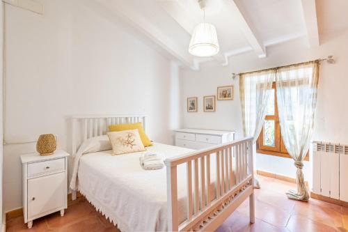 a white bedroom with a bed and a window at Finca Can Quadrat by Mallorca House Rent in Caʼs Concos