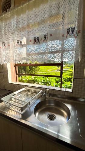 a sink in front of a window with a curtain at Chalés Paraíso das Ilhas - Alto Cedros. in Rio dos Cedros