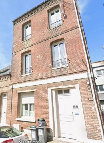 un bâtiment en briques avec une porte de garage blanche dans l'établissement L'Escapade Mersoise, à Mers-les-Bains