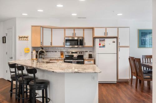 a kitchen with a white refrigerator and a counter with stools at Lake Hideaway - Waterfront Condo with Resort Perks in Kimberling City