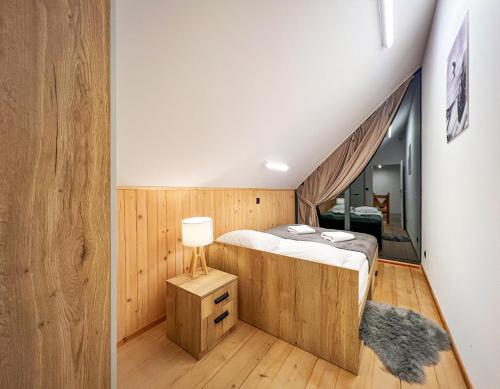 um quarto com uma cama e um candeeiro num piso de madeira em POLANA PIORUN Domki całoroczne w Beskidach em Krynica Zdrój