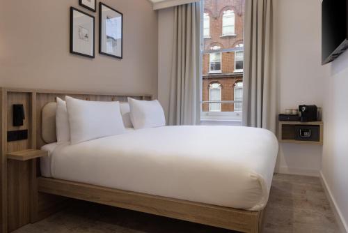 a bedroom with a white bed and a window at The Drey - Kensington, Earl's Court in London