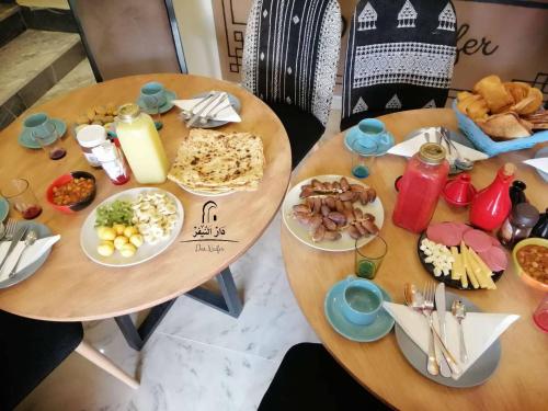 two wooden tables with plates of food on them at Dar Naifer in Tozeur