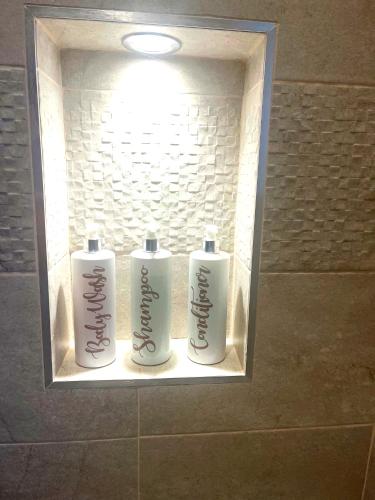 two white bottles ofodorizers in a niche in a bathroom at The Stables, a delightful 3 bed house near the Norfolk Broads in Upton