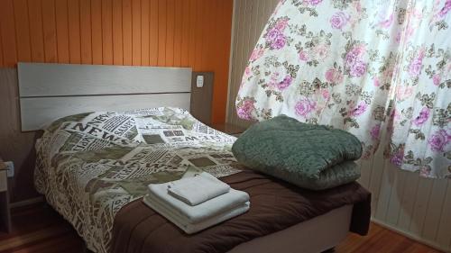 a bed with two towels sitting on top of it at Chalé Paraíso Da Serra 01 in Gramado