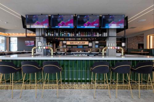 a bar with chairs and televisions above it at Sandman Signature Glasgow Hotel in Glasgow