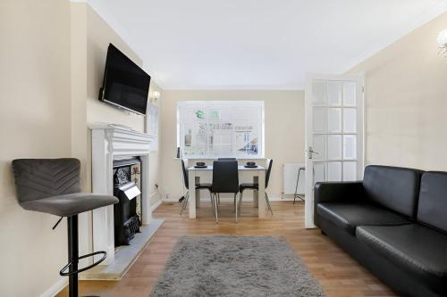 a living room with a black couch and a table at 5-Bed House with Garden Near Warner Bros Studios in Hemel Hempstead