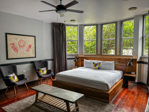 a bedroom with a bed and two chairs and windows at Viajero San José Hostel in San José