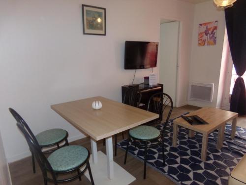 a living room with a table and chairs and a tv at La Belle Onde in Dieppe