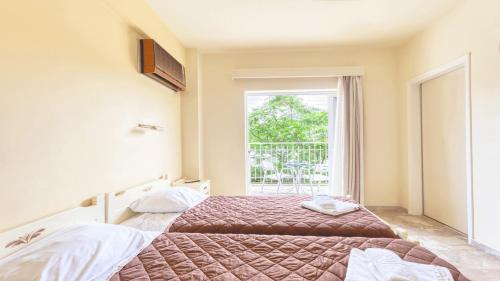 a bedroom with two beds and a window at Akrotopi Apartments & Studios in Tolo