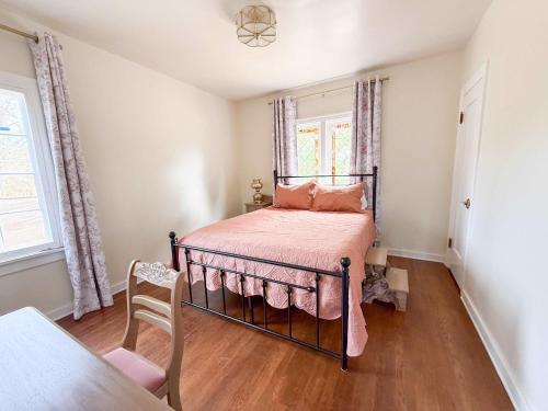 The Vintage La Mesa Tudor في Spring Valley: غرفة نوم مع سرير وملاءات وردية وكرسي