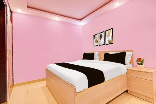 a bedroom with a bed and a pink wall at Hotel O Sky House Residency in New Delhi