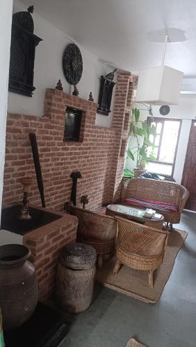 a living room with a brick fireplace and wicker chairs at Easy Homes - Ashok Stupa in Pātan