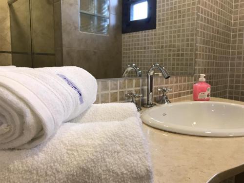 a bathroom with towels on a counter next to a sink at La Osadia Cabañas y Suites Solo Adultos in Mina Clavero