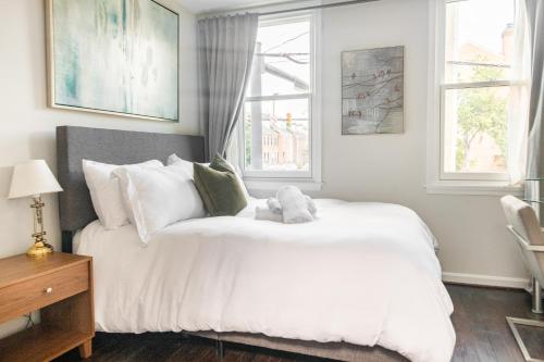 a bedroom with a large white bed with windows at King Bed & Fenced Yard - Floyd's Freedom- in Alexandria