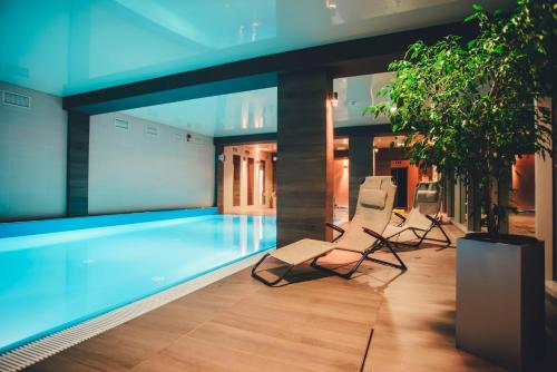 a pool with two lounge chairs and a swimming pool at Hotel Trojan in Lądek-Zdrój