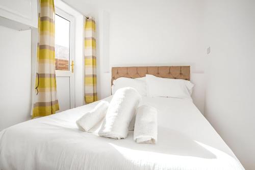 a white bed with two white towels on it at 5-Bed House with Garden Near Warner Bros Studios in Hemel Hempstead