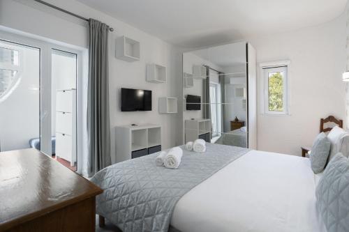 a white bedroom with a bed and a mirror at Sun & Sea Flat Quarteira - by Hopstays in Cavacos