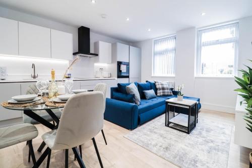 a living room with a blue couch and a table at The Wycombe Pad - 2BR Ground Floor Apt with A Private Entrance & Free Secure Underground Parking in High Wycombe