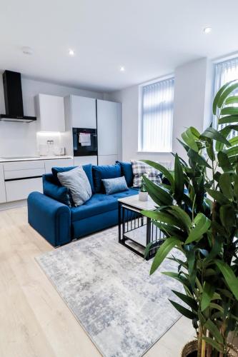 a living room with a blue couch and a table at The Wycombe Pad - 2BR Ground Floor Apt with A Private Entrance & Free Secure Underground Parking in High Wycombe