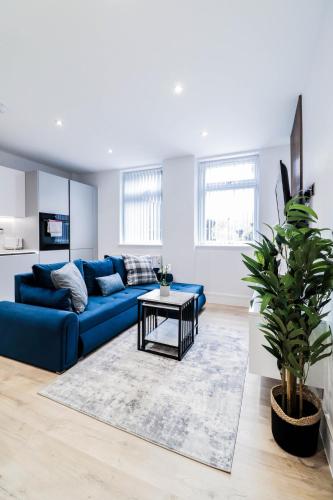 a living room with a blue couch and a table at The Wycombe Pad - 2BR Ground Floor Apt with A Private Entrance & Free Secure Underground Parking in High Wycombe