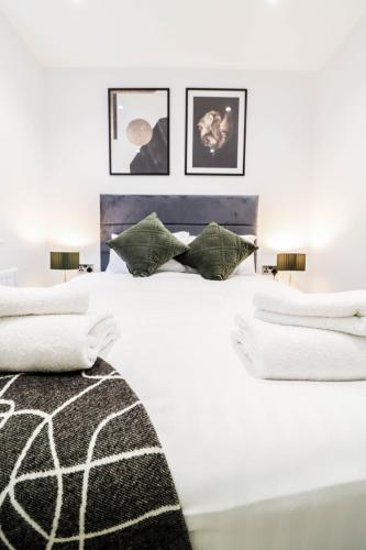 a white bedroom with a large white bed with pillows at The Wycombe Pad - 2BR Ground Floor Apt with A Private Entrance & Free Secure Underground Parking in High Wycombe