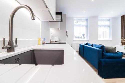a kitchen with a sink and a blue couch at The Wycombe Pad - 2BR Ground Floor Apt with A Private Entrance & Free Secure Underground Parking in High Wycombe