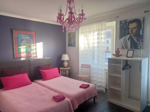 a bedroom with two beds with pink sheets and a chandelier at La Maison de Soso in Chambon-le-Château