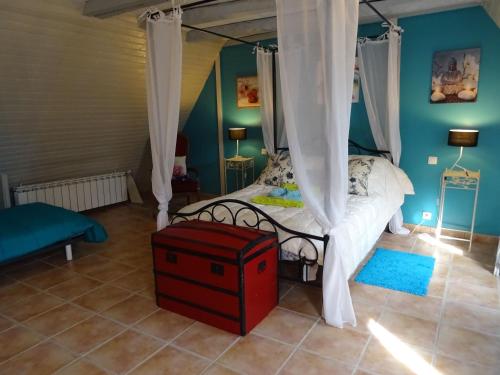 BrandonnetManoir Les Hortensias的一间卧室，里面有一张带顶篷的床，床边放着一个红色箱子。