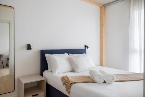 a bedroom with a bed with white pillows and a mirror at Calido Valdebebas in Madrid