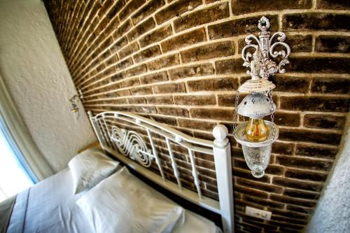 a lamp hanging on a brick wall next to a bed at Villa Fanti in Cesme