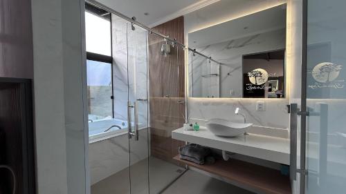 un bagno con lavandino e doccia in vetro di Rancho Ipês do Lago a Socorro