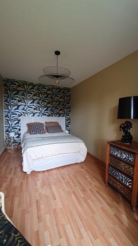 a bedroom with a bed and a table with a lamp at Longère chez Martine et Julie in Romorantin