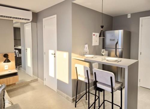a kitchen with a bar with stools and a refrigerator at A7 Vix by Housi – studios e apartamentos modernos em Vitória in Guajuru