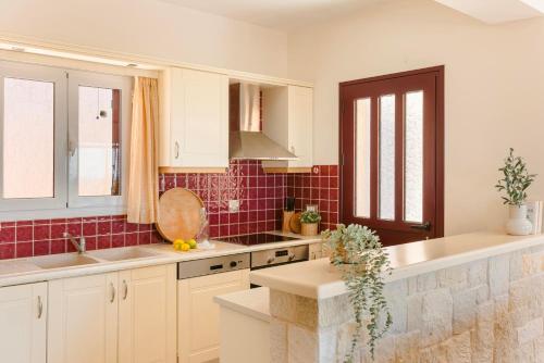 a kitchen with white cabinets and red tile at Dina by Vintage Travel in Kaligata