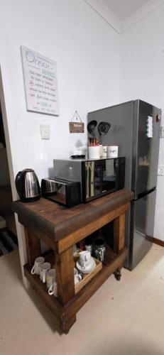a microwave sitting on a table next to a refrigerator at Lazey Bazely Beach Cottage in Bazley Beach