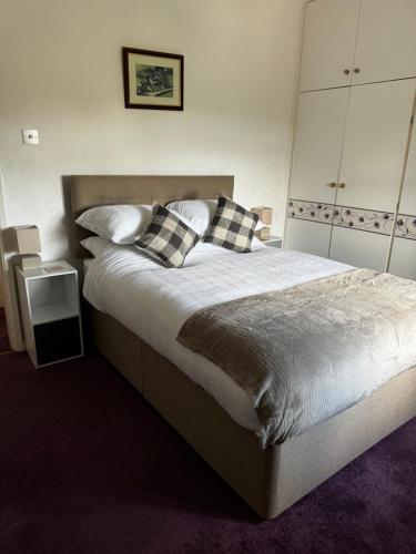 a bedroom with a large bed with checkered pillows at Goosemoor Cottage in Longdon