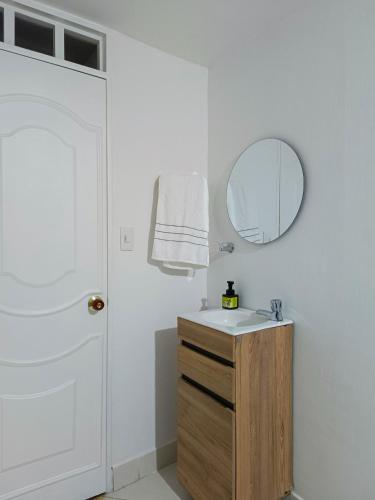 a white bathroom with a sink and a mirror at Apartamento Ideal Climatizado con Encanto Cultural in Buga