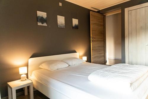 a bedroom with a white bed with two pillows at l'hôt'antique in Vielsalm