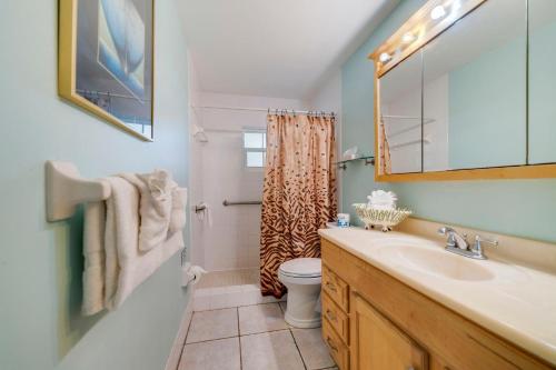 Un baño con lavabo, inodoro y espejo. en Beach Place Guesthouses, en Cocoa Beach