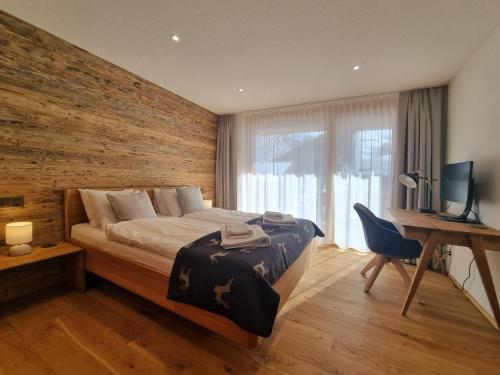Un dormitorio con una cama y un escritorio con una computadora. en Berghof 2nd Floor, en Saas-Fee