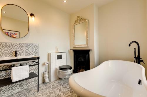 a bathroom with a tub and a toilet and a mirror at The Royal Paddock in Ascot