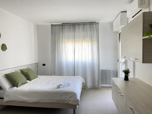 a white bedroom with a bed and a window at Monolocale vicino Pordenone Fiera 