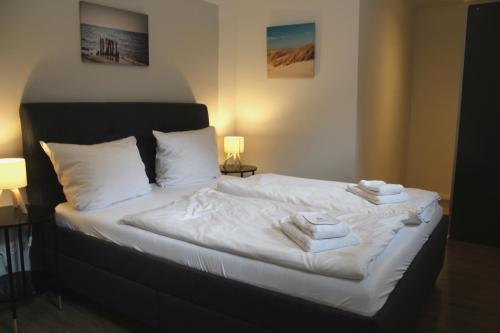 ノイシュタット・イン・ホルシュタインにあるFairschlafen am Hafenのベッド(白いシーツ、タオル付)