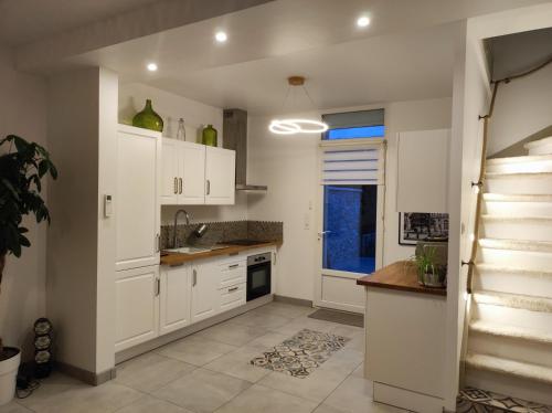 eine Küche mit weißen Schränken und einer Treppe in der Unterkunft Maison moderne au calme,coeur de ville-3 chambres 2 sdb in Sens