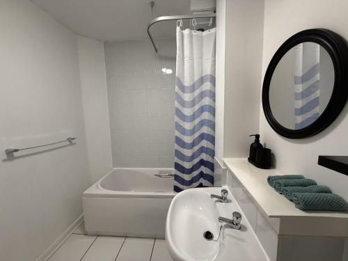une salle de bain avec un lavabo, une baignoire et un miroir dans l'établissement Newly furnished comfortable property!, à Dalmuir