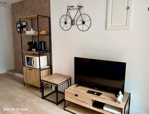 ein Wohnzimmer mit einem TV und einem Fahrrad an der Wand in der Unterkunft Chez les filles Defrance in Royat