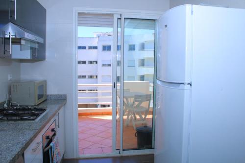 a kitchen with a refrigerator and a table with a balcony at BOUZNIKA Appartement avec piscine in Bouznika
