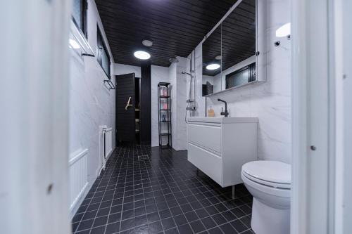 baño con aseo blanco y suelo de baldosa negra en Arctic Aurora Villa With Sauna - Northern Lights and Adventures in the Hometown of Santa Claus, Rovaniemi, en Rovaniemi
