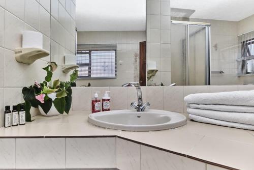 ein weißes Badezimmer mit Waschbecken und Spiegel in der Unterkunft Villa Picasso - 3 Bed Villa in Johannesburg